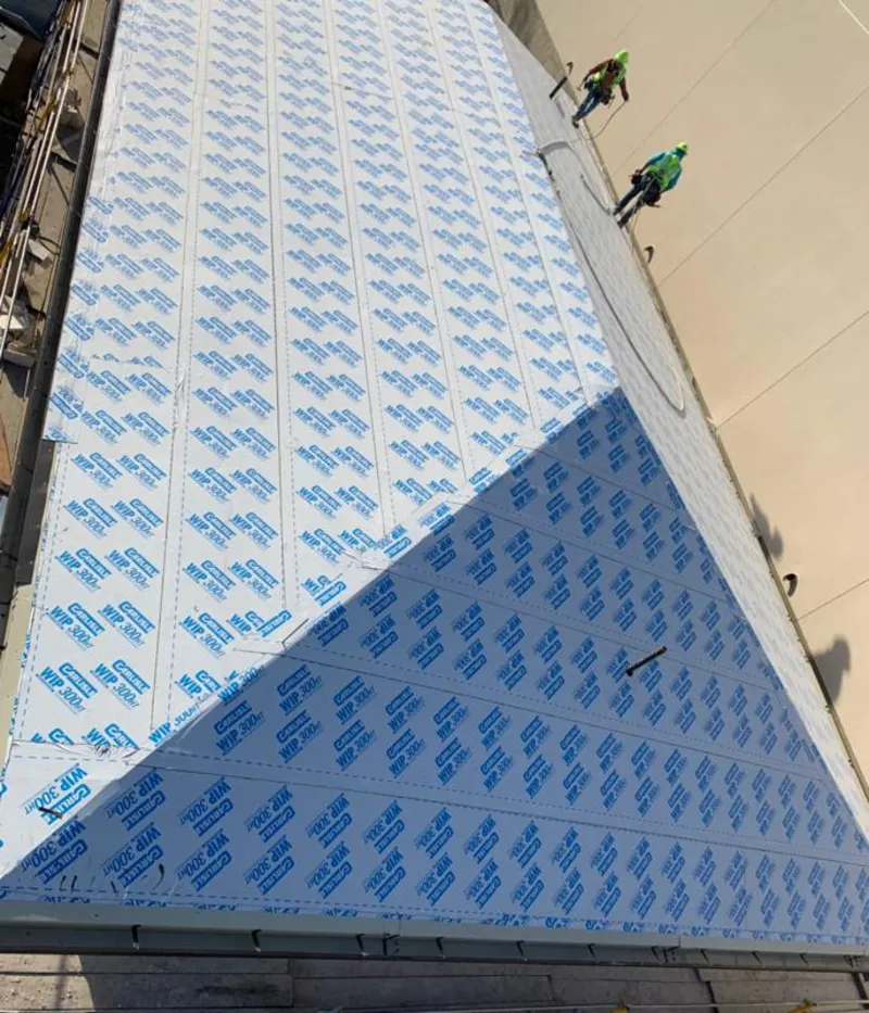 Professional roofers installing underlayment on a metal roof in East Greenwich